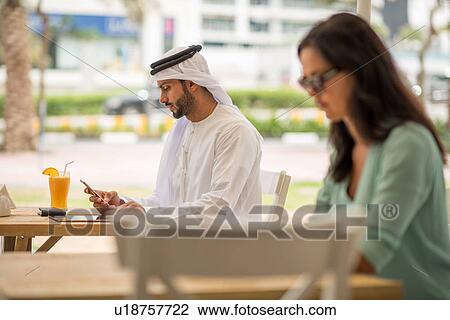 Middle eastern man wearing traditional clothing reading smartphone text at cafe, Dubai, United Arab Emirates View Large Photo Image Stock Image - Middle eastern man wearing traditional clothing reading smartphone text at cafe, Dubai, United Arab Emirates. Fotosearch