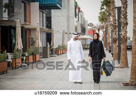 Middle eastern shopping couple wearing traditional clothing carrying shopping bags, Dubai, United Arab Emirates View Large Photo Image Stock Photo - Middle eastern shopping couple wearing traditional clothing carrying shopping bags, Dubai, United Arab Emirates. Fotosearch