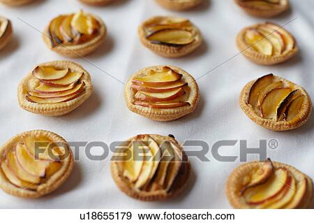 Stock Photo - Miniature frangipane apple tarts on tablecloth. Fotosearch