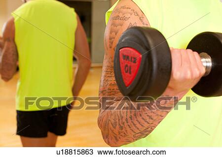 Mirror image of man in gym using dumbbell View Large Photo Image Stock Image - Mirror image of man in gym using dumbbell. Fotosearch