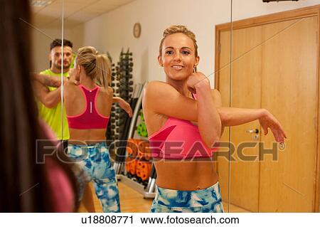 Mirror image of people in gym doing arm stretching exercises View Large Photo Image Stock Image - Mirror image of people in gym doing arm stretching exercises. Fotosearch