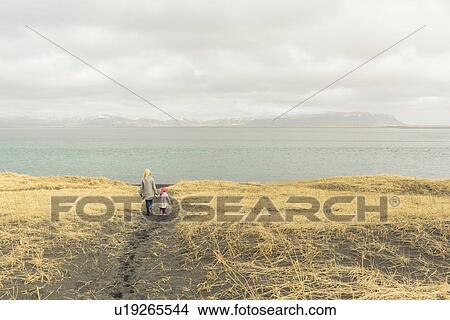 Mother and daughter, holding hands, walking towards beach, rear view, Eyrarbakki, Iceland View Large Photo Image Picture - Mother and daughter, holding hands, walking towards beach, rear view, Eyrarbakki, Iceland. Fotosearch