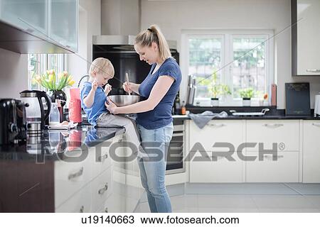 Stock Image - Mother and son baking together, stirring mixture in mixing bowl. Fotosearch