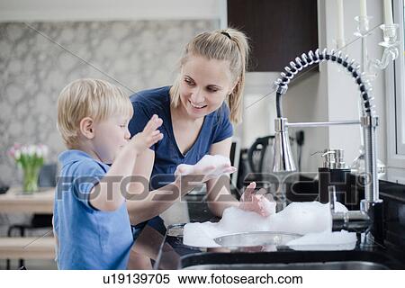 Stock Photography - Mother and son doing washing up together. Fotosearch