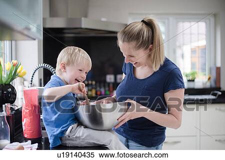 Stock Photography - Mother and son fooling around whilst baking, stirring mixture in mixing bowl. Fotosearch