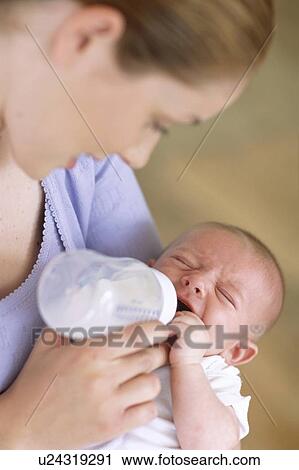 Stock Image - Mother bottle-feeding baby boy. Fotosearch