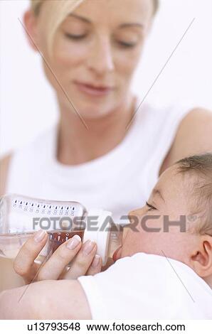 Stock Photo - Mother bottle-feeding baby boy. Fotosearch
