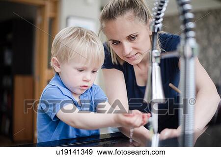 Stock Photo - Mother helping son wash his hands. Fotosearch