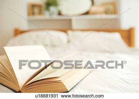 Stock Image - Open book on top of bed. Fotosearch