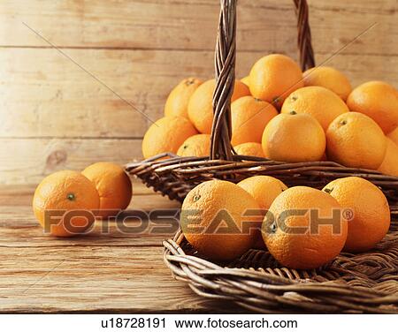 Stock Image - Oranges in wicker basket and on wicker plate. Fotosearch