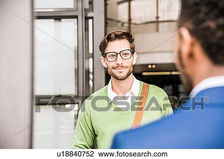 Over shoulder view of two businessmen meeting outside office building View Large Photo Image Stock Image - Over shoulder view of two businessmen meeting outside office building. Fotosearch