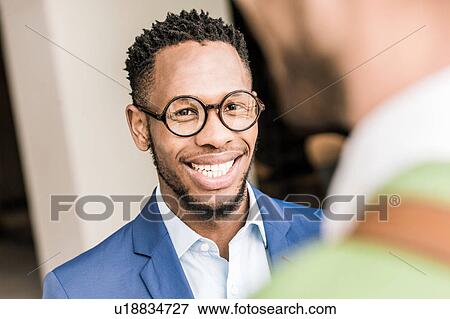 Stock Photo - Over shoulder view of two businessmen having discussion outside office building. Fotosearch