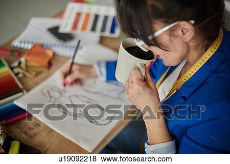 Over shoulder view of woman in design studio drinking coffee, sketching fashion design View Large Photo Image Stock Photo - Over shoulder view of woman in design studio drinking coffee, sketching fashion design. Fotosearch