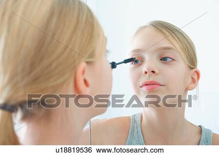 Over the shoulder mirror image of girl applying mascara View Large Photo Image Stock Photograph - Over the shoulder mirror image of girl applying mascara. Fotosearch