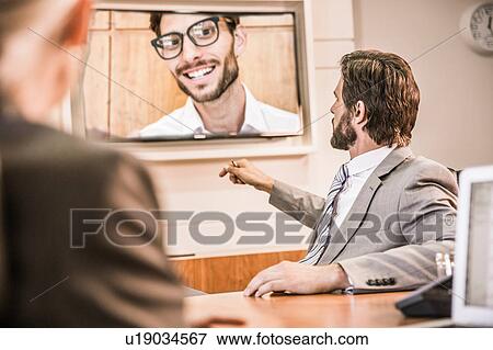 Over the shoulder view of business people in boardroom having video call meeting View Large Photo Image Stock Photo - Over the shoulder view of business people in boardroom having video call meeting. Fotosearch