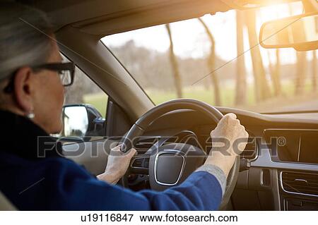 Over the shoulder view of woman in car driving on tree lined road View Large Photo Image Stock Photo - Over the shoulder view of woman in car driving on tree lined road. Fotosearch