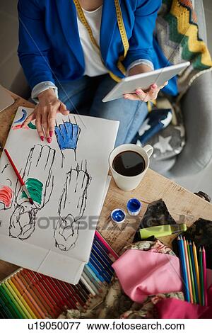 Stock Photo - Overhead view of woman in design studio using digital tablet. Fotosearch