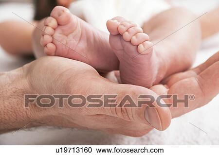 Stock Image - Parent holding newborn baby's feet. Fotosearch