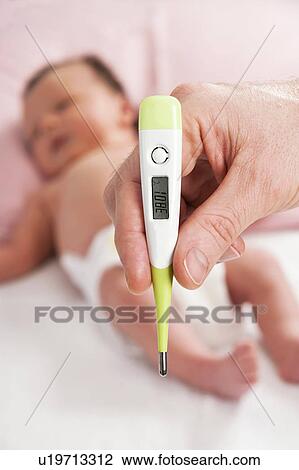 Stock Image - Parent taking newborn baby's temperature. Fotosearch