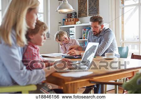 Stock Photograph - Parents and sons working in home office. Fotosearch