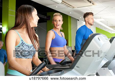 People at gym using exercise machines chatting View Large Photo Image Stock Photograph - People at gym using exercise machines chatting. Fotosearch