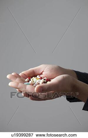Stock Photo - Person holding pills in cupped hands. Fotosearch