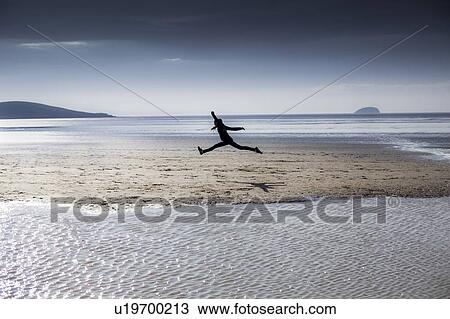 Stock Image - Person leaping on a beach. Fotosearch