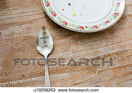 Stock Image - Plate and spoon engraved with slogan on wooden surface. Fotosearch