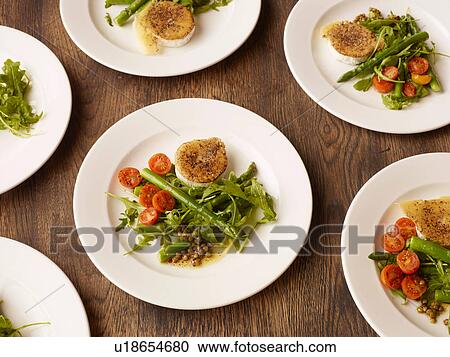 Stock Image - Plates of peppered fried goats cheese and salad. Fotosearch