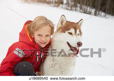 Stock Image - Portrait of boy and husky in snow, Elmau, Bavaria, Germany. Fotosearch