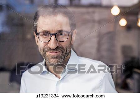 Portrait of confident businessman looking through office window View Large Photo Image Picture - Portrait of confident businessman looking through office window. Fotosearch