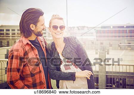 Stock Image - Portrait of cool mid adult couple on rooftop parking lot. Fotosearch