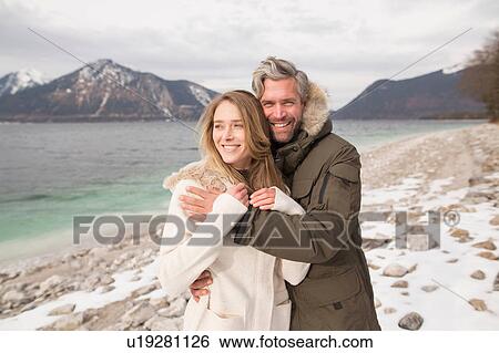 Stock Photograph - Portrait of couple beside lake, smiling, German Alps, Germany. Fotosearch