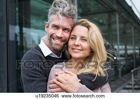 Stock Photograph - Portrait of couple outdoors, smiling, man hugging woman. Fotosearch