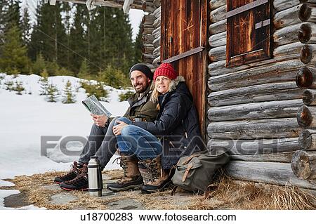 Portrait of couple reading map sitting outside log cabin in winter, Elmau, Bavaria, Germany View Large Photo Image Stock Image - Portrait of couple reading map sitting outside log cabin in winter, Elmau, Bavaria, Germany. Fotosearch
