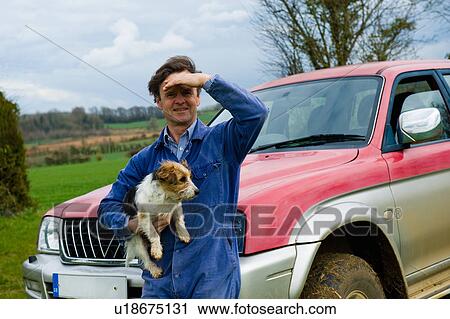 Stock Image - Portrait of farmer carrying dog. Fotosearch