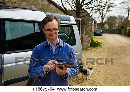 Portrait of farmer outside farmhouse texting on smartphone View Large Photo Image Picture - Portrait of farmer outside farmhouse texting on smartphone. Fotosearch