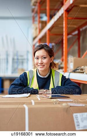 Stock Image - Portrait of female factory worker in factory warehouse. Fotosearch