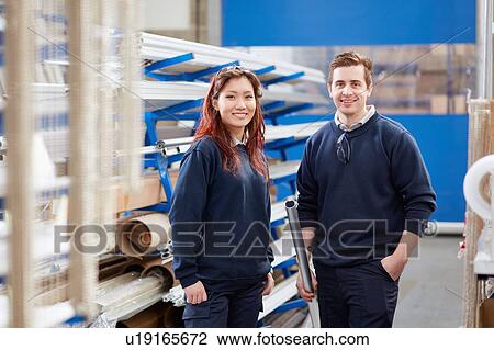 Stock Image - Portrait of manger and young female worker in roller blind factory. Fotosearch