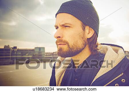 Picture - Portrait of mid adult man wearing knit hat on rooftop parking lot. Fotosearch