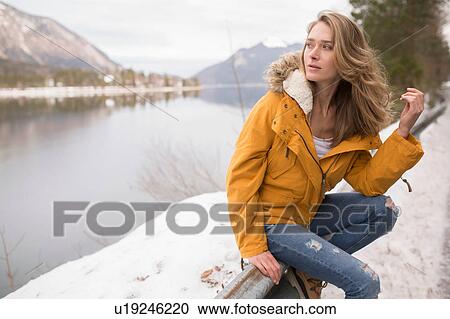 Portrait of mid adult woman sitting on railing by side of road, German Alps, Germany View Large Photo Image Stock Image - Portrait of mid adult woman sitting on railing by side of road, German Alps, Germany. Fotosearch