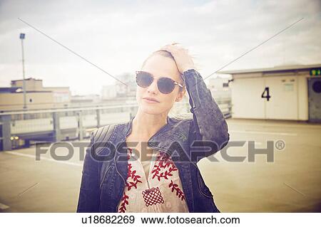 Portrait of mid adult woman wearing shades on rooftop parking lot View Large Photo Image Stock Photo - Portrait of mid adult woman wearing shades on rooftop parking lot. Fotosearch