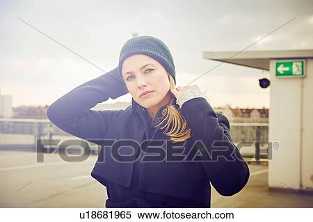 Stock Photography - Portrait of mid adult woman wearing knit hat on rooftop parking lot. Fotosearch