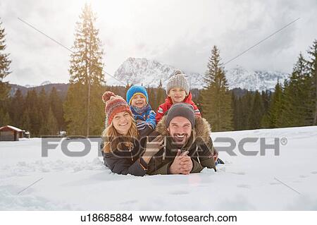 Portrait of parents and sons lying in snow covered landscape, Elmau, Bavaria, Germany View Large Photo Image Picture - Portrait of parents and sons lying in snow covered landscape, Elmau, Bavaria, Germany. Fotosearch
