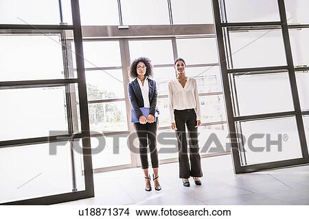 Picture - Portrait of two young businesswomen at office entrance. Fotosearch