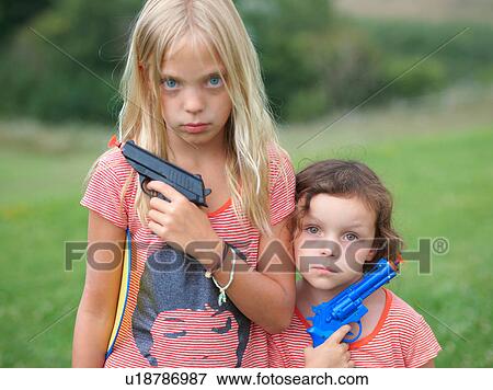Portrait of two young sisters, holding toy guns View Large Photo Image Stock Photo - Portrait of two young sisters, holding toy guns. Fotosearch