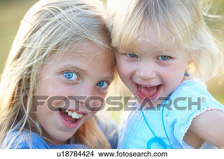 Picture - Portrait of two young sisters, outdoors, smiling. Fotosearch