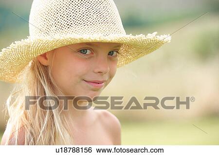 Stock Photograph - Portrait of young girl outdoors, wearing straw hat. Fotosearch