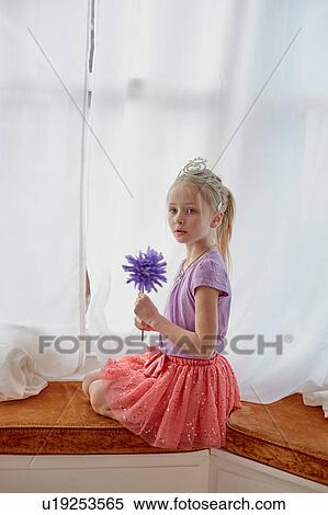 Portrait of young girl sitting by widow, wearing tiara, holding wand View Large Photo Image Stock Photography - Portrait of young girl sitting by widow, wearing tiara, holding wand. Fotosearch