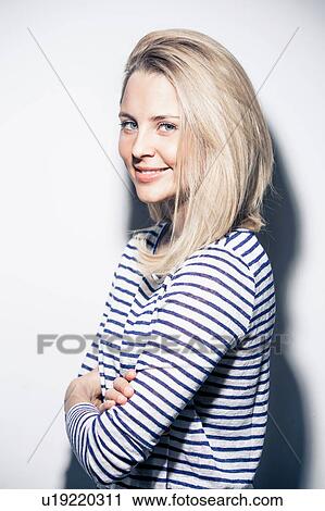 Portrait of young woman, arms folded, smiling View Large Photo Image Stock Image - Portrait of young woman, arms folded, smiling. Fotosearch